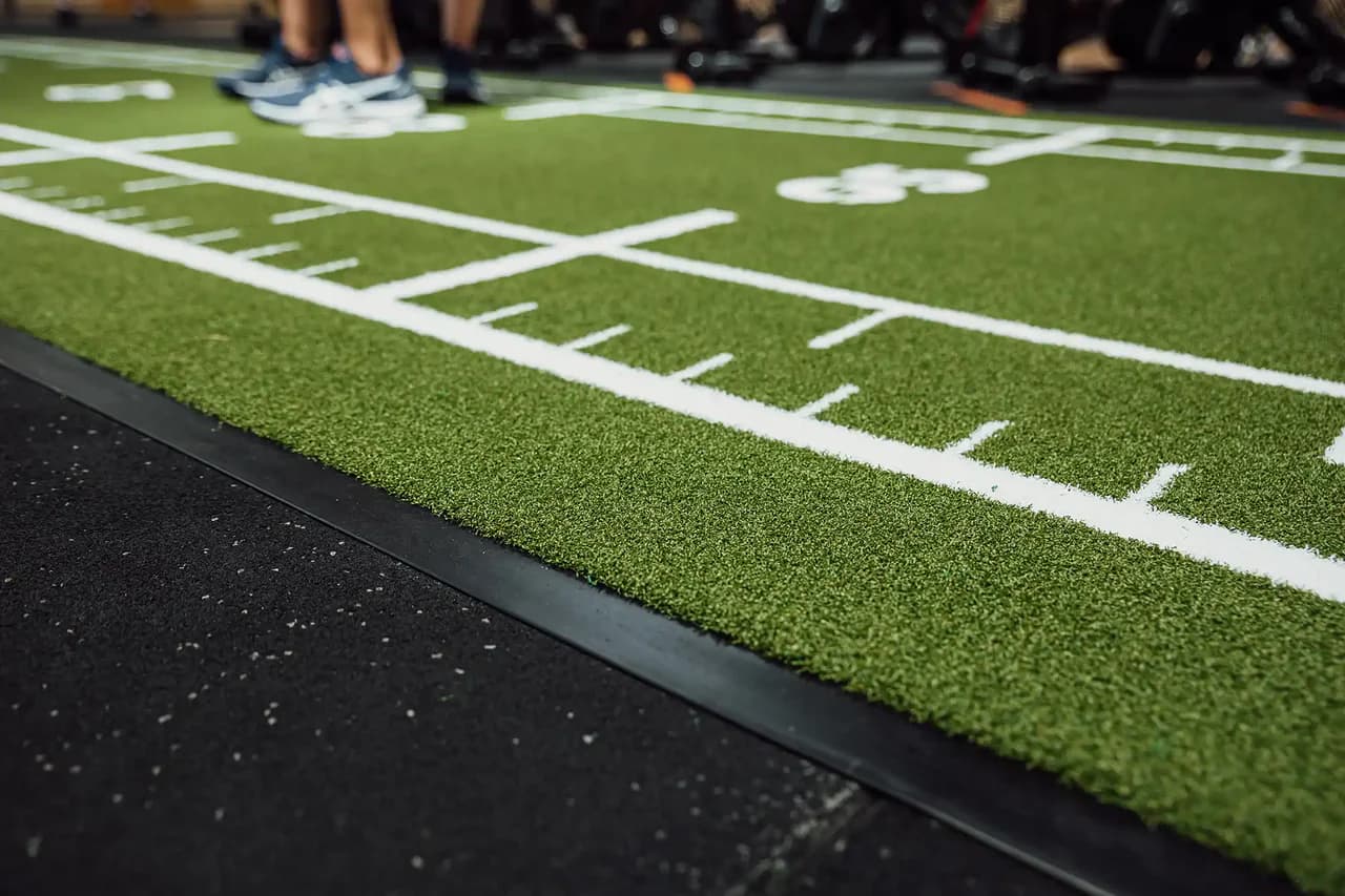 Close-up van een groene Heroturfs-sledbaan met witte markeringen in een sportschool